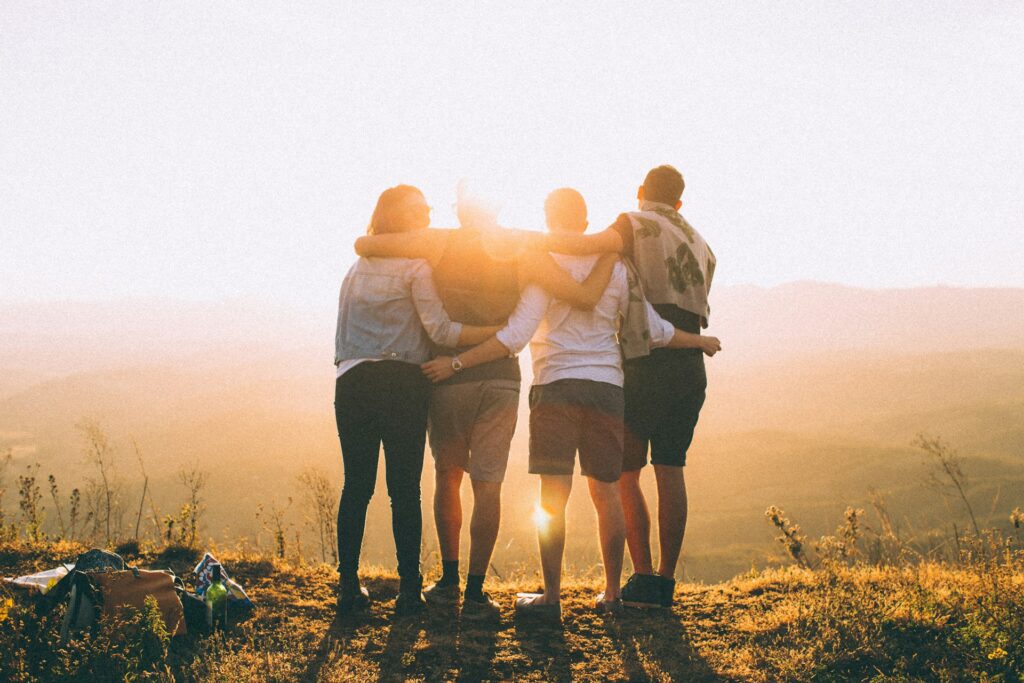 A group of four people watching the sunset on a hill